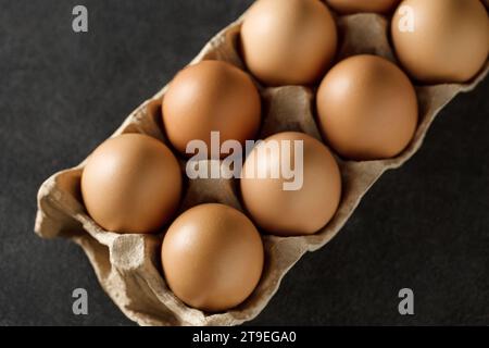Œufs de poule entiers dans un plateau sur fond sombre, mise au point sélective. Banque D'Images