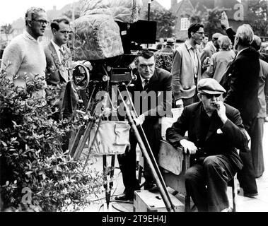 JACK HAWKINS réalisateur JOHN FORD et le cinéaste FREDDIE YOUNG (à l'extrême droite) sur place Candid avec film / Movie Crew pendant le tournage de GIDEOn'S DAY / GIDEON OF SCOTLAND YARD 1958 réalisateur JOHN FORD Novel John Creasey scénario T.E.B. Clarke Columbia British Productions Banque D'Images
