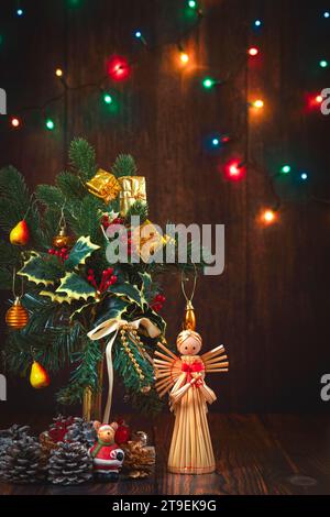 Arrangement de fleurs de Noël, décoration, lumières de fée, ange de paille, fond en bois Banque D'Images