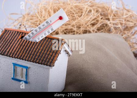 Thermomètre mesurant la température élevée placé sur une petite maison modèle Banque D'Images