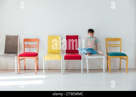 garçon et de nombreuses chaises différentes à l'intérieur d'une pièce blanche Banque D'Images