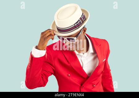 Jeune homme afro-américain tendance dans des lunettes de soleil élégantes et veste rouge vif se tient en studio Banque D'Images