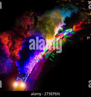 Kingswear, Devon, Royaume-Uni. 24 novembre 2023. Le train des lumières de Noël sur le chemin de fer à vapeur de Dartmouth dans le Devon, qui circule entre le 24 novembre et le 30 décembre 2023, se dirige vers Paignton alors qu'il voyage à côté de la rivière Dart après avoir quitté Kingswear. Les voitures et les locomotives à vapeur du service festif sont éclairées à l'intérieur et à l'extérieur avec des lumières colorées. Crédit photo : Graham Hunt/Alamy Live News Banque D'Images