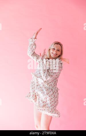 Femme souriant et dansant à la musique sur fond rose Banque D'Images