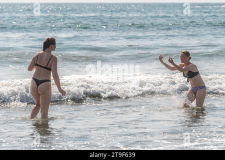 Deux femmes vêtues de bikini s'amusent dans la mer à Warren Beach, Rosscarbery, West Cork, Irlande. Banque D'Images