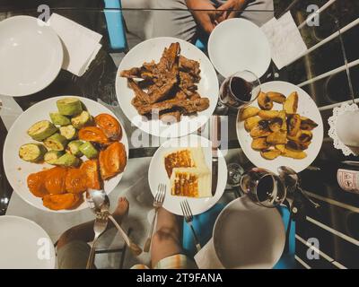 vue de dessus de la table avec dîner. Viande BBQ, légumes grillés, fromage grillé, verres de vin. pose à plat. flou artistique Banque D'Images