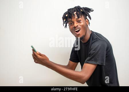 photo d'un jeune homme noir sur dreadlocks envoyant un message sur un téléphone portable. Heureux homme afro-américain utilisant smartphone, appréciant le chat en ligne, messagi Banque D'Images