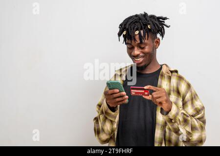 Jeune homme à l'aide du téléphone portable et de la carte atm, achats en ligne Banque D'Images