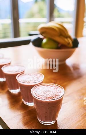 Milk-shake aux fruits maison, quelques verres dans une rangée placés sur une table en bois Banque D'Images