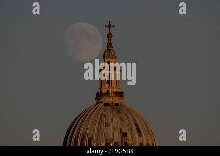 Londres, Royaume-Uni. 25 novembre 2023. Météo au Royaume-Uni - Une lune gibbeuse cireuse de 96,3% est vue se lever derrière St. Cathédrale de Paul. La pleine lune de ce mois-ci atteint son illumination maximale le 27 novembre et est connue sous le nom de Beaver Moon, ainsi nommée quand les castors commencent à s’abriter dans leurs loges, après avoir installé suffisamment de magasins d’alimentation pour le long hiver à venir. Crédit : Stephen Chung / Alamy Live News Banque D'Images