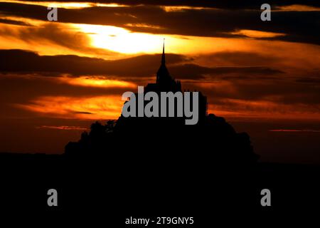 Le soleil se couche derrière la silhouette noire de l'ancienne abbaye du Mont Saint Michel dans la région du Nord de la France Banque D'Images