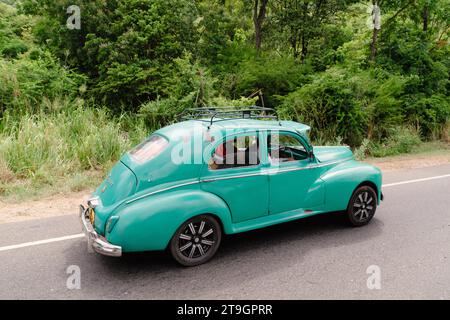 Une vieille voiture classique verte voyage le long d'une route au Sri Lanka près de Mirissa Banque D'Images