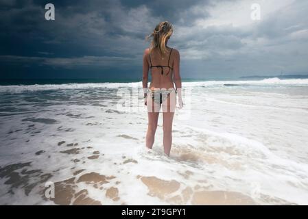 Une femme en bikini se tient au bord de la mer sur la plage de Tangalle au Sri Lanka par temps couvert Banque D'Images