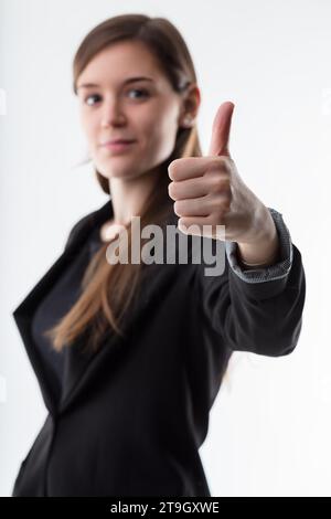 pouces levés ! au premier plan, jeune femme d'affaires floue en arrière-plan. Acceptez et soutenez votre choix. C'est bien parti ! Banque D'Images