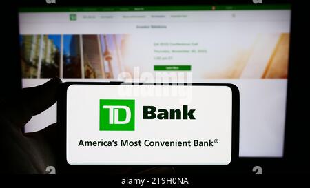 Personne détenant un téléphone intelligent avec le logo de la société de services financiers Banque Toronto-Dominion (TD) devant le site Web. Concentrez-vous sur l'affichage du téléphone. Banque D'Images