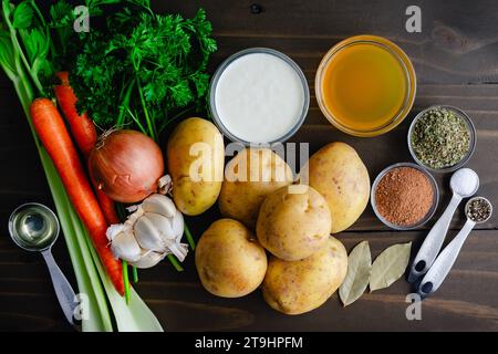 Soupe allemande de pommes de terre (Kartoffelsuppe) Ingrédients sur une table en bois : pommes de terre jaunes fraîches avec d'autres légumes, herbes et épices pour une recette de soupe Banque D'Images