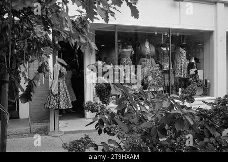 Salem, Massachusetts - Une vitrine lumineuse remplie de robes vintage exposées pour les touristes avec des fleurs en fleurs au premier plan. Le i Banque D'Images