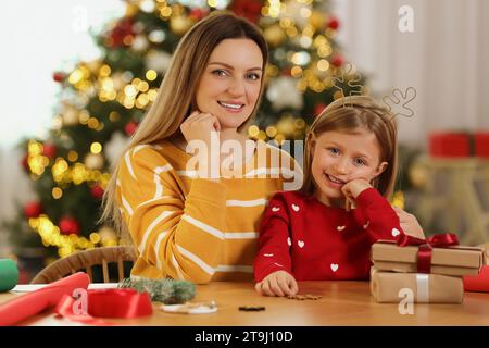 Emballage de cadeaux de Noël. Mère heureuse et sa petite fille à table avec des coffrets cadeaux dans la chambre Banque D'Images