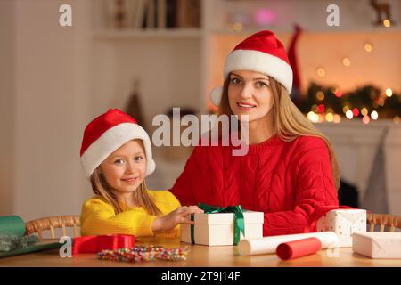 Emballage de cadeaux de Noël. Mère et sa petite fille avec boîte cadeau à table dans la chambre Banque D'Images