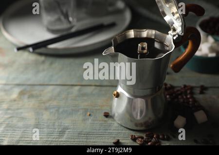 Café infusé dans un pot moka, haricots et cubes de sucre sur une table en bois rustique, espace pour le texte Banque D'Images