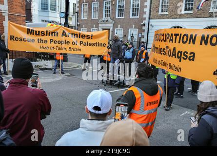 Londres, Royaume-Uni. 25 novembre 2023. Les manifestants brandissent de grandes banderoles à l'avant de la manifestation disant « les armées musulmanes sauvent le peuple de Palestine » alors qu'un orateur s'adresse à la foule. Hizb ut-Tahrir organise une manifestation statique face à l'ambassade égyptienne appelant les armées musulmanes à sauver le peuple palestinien. Les conditions de l'article 14 de la Loi sur l'ordre public signifient qu'ils ne peuvent pas quitter Balfour Mews. Hizb ut-Tahrir affirme son objectif comme l'unification de toutes les terres musulmanes au fil du temps dans un État islamique unitaire ou un califat et la mise en œuvre de la charia à l'échelle mondiale. Crédit : SOPA Images Limited/Alamy Live News Banque D'Images