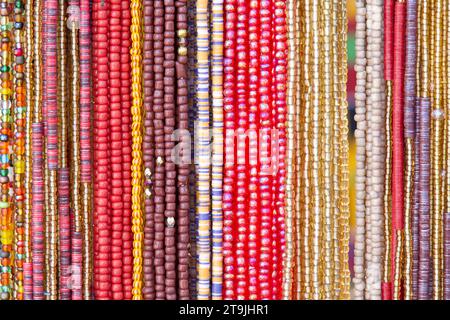 gros plan sur des cordes de perles en rouge, jaune, rose. Décorations de cheveux populaires dans certaines cultures. Banque D'Images