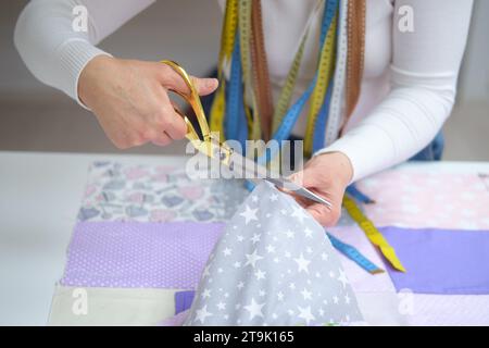 Gros plan des mains féminines coupant le tissu avec des ciseaux. Concept de couture Banque D'Images