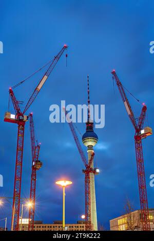 La célèbre tour de télévision de Berlin la nuit avec quatre grues de construction rouges Banque D'Images