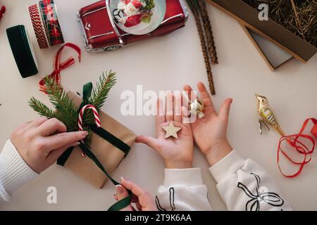 Vue de dessus de maman et fille emballant des cadeaux pour la veille de Noël. Famille heureuse passer du temps plus dur pendant les vacances d'hiver Banque D'Images