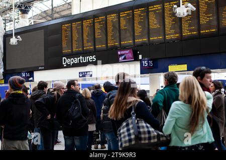 Groupe de personnes regardant le tableau des départs électroniques à la gare de Paddington à Londres Banque D'Images