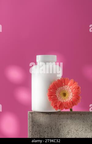 Mockup est un pot blanc avec des pilules ou des vitamines sur un podium. Vitamines pour femmes Banque D'Images