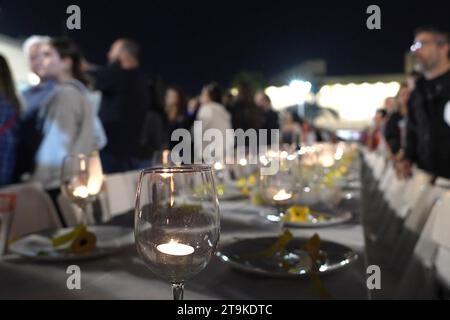 Une table de Shabbat organisée de manière festive avec des chaises vides, représentant les otages israéliens du Hamas, se tient debout alors que des dizaines de milliers de personnes assistent à un rassemblement en soutien aux 212 otages qui sont toujours détenus par le Hamas, alors que 13 autres otages israéliens ont été libérés de Gaza, au cours de la deuxième journée du cessez-le-feu le 25 novembre 2023 à tel Aviv, Israël. Au total, 50 otages actuellement détenus par le Hamas doivent être libérés au cours d'une trêve de quatre jours avec Israël Banque D'Images