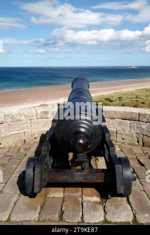 canon du château de Bamburgh regardant notre sur les sables. Northumberland, Royaume-Uni Banque D'Images