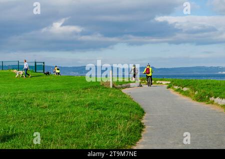 Crawfordsburn, County Down, Irlande du Nord octobre 10 2023 - des cyclistes sur le sentier côtier de Crawfordsburn et un homme promenant deux chiens Banque D'Images