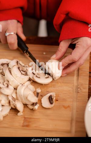 L'expertise culinaire en action comme une femme prépare habilement les champignons sur un bloc de coupe en bois Banque D'Images