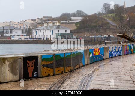 Swanage, Dorset Royaume-Uni. 26 novembre 2023. Météo Royaume-Uni : temps humide, gris et sombre à Swanage dans le Dorset. Peintures sur la barrière temporaire des vagues hivernales de Swanage les blocs de béton mis en place par l’Agence de l’environnement pour réduire l’impact des inondations, ajoutent de la couleur à une journée grise! Crédit : Carolyn Jenkins/Alamy Live News Banque D'Images