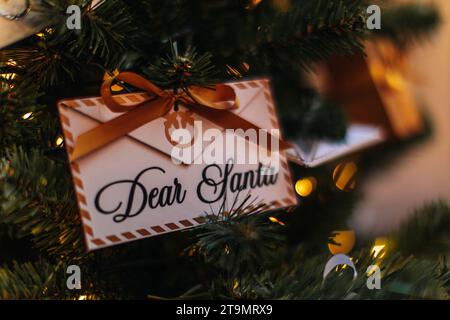 Lettre papier magique avec texte Dear santa et ruban soyeux accroché sur le sapin de Noël. Décoration de vacances d'hiver Banque D'Images