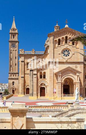 Ta Pinu, Malte - 26 août 2019 : la basilique du sanctuaire national de la Sainte Vierge de Ta Pinu par une journée ensoleillée, les gens marchent dans la rue Banque D'Images