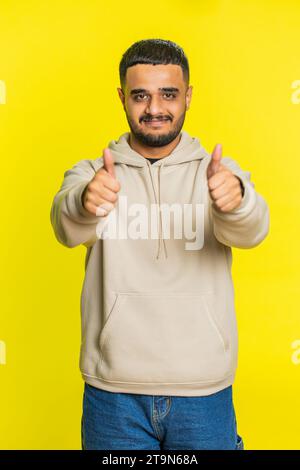 J'aime. L'homme indien soulève les pouces vers le haut est d'accord avec quelque chose ou donne une réponse positive recommande la publicité aime la rétroaction de bonne idée, célébrant la victoire de succès. Guy sur fond jaune. Vertical Banque D'Images