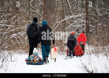 Loisirs en famille sur la nature hivernale, couple avec enfants se rendent au parc pour rouler sur des tubes à neige Banque D'Images