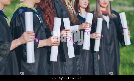 Rouleaux de diplômes entre les mains d'un groupe de diplômés. Banque D'Images