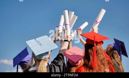 Les diplômés collégiaux avec casquettes lient leurs diplômes ensemble. Banque D'Images