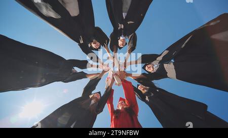 Les diplômés collégiaux joignent leurs mains avec des diplômes debout dans un cercle. Banque D'Images