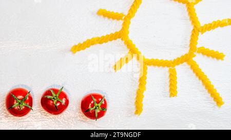 Soleil fait de pâtes fusilli, champ vert fait de pâtes vertes en spirale et tomates cerises, concept de culture de tomates sur fond blanc Banque D'Images