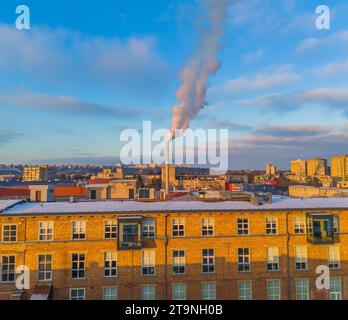 Vue aérienne drone de la pollution dans une ville. Fumée blanche provenant d'une cheminée industrielle située dans le centre de la grande ville avec des zones résidentielles autour. Banque D'Images