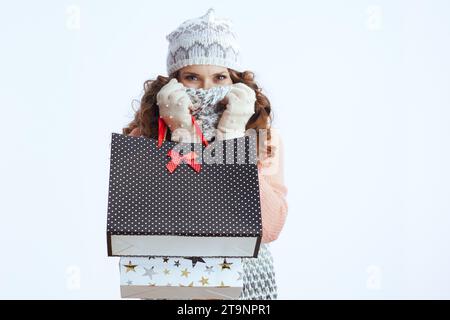 Bonjour l'hiver. femme élégante en pull, mitaines, chapeau et écharpe isolé sur fond blanc avec des sacs à provisions. Banque D'Images