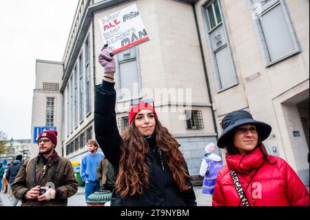 Une femme est vue soutenant la manifestation debout avec une pancarte sur le côté de la rue. A l'occasion de la Journée internationale contre la violence à l'égard des femmes, et à l'initiative de Mirabal Belgium (un groupe de plusieurs associations de la société civile), une nouvelle manifestation nationale de lutte contre la violence à l'égard des femmes a eu lieu dans la capitale belge. Des milliers de personnes ont défilé en cette journée pour envoyer un signal fort en faveur de l'élimination de la violence à l'égard des femmes et appeler la société civile (associations et citoyens) à exprimer leur rejet de la violence "machiste". Banque D'Images