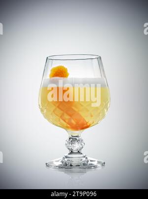 Verre de cocktail d'alcool classique Whiskey Sour avec jus de citron et blanc d'oeuf sur fond gradué Banque D'Images