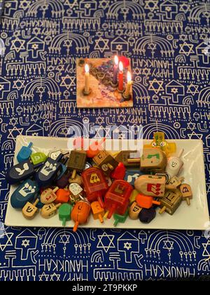 ÉTATS-UNIS. 12 décembre 2020. La 3e nuit de Chanucha plus la bougie shamash (aide) sur une menorah. Une assiette de Draidels - un jeu traditionnel à jouer pendant Hanukkah. Souvent, les enfants jouent pour des bonbons de monnaie de chocolat ou de l'argent. Crédit photo : Robyn Stevens Brody/Sipa USA. Crédit : SIPA USA/Alamy Live News Banque D'Images