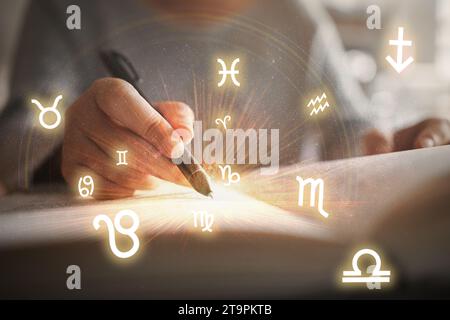 Femme lisant un livre d'astrologie. Projection de roue astrologique, choisissez un signe du zodiaque. Astrologie concept ésotérique. Banque D'Images